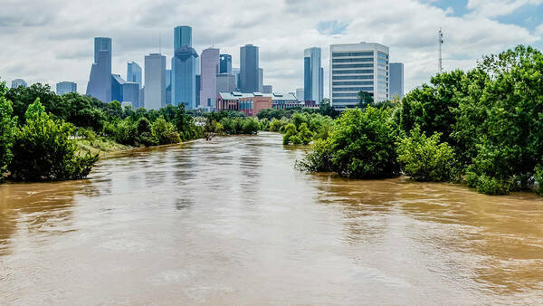 Brown, flooded waterway in front of Houston skyscrapers